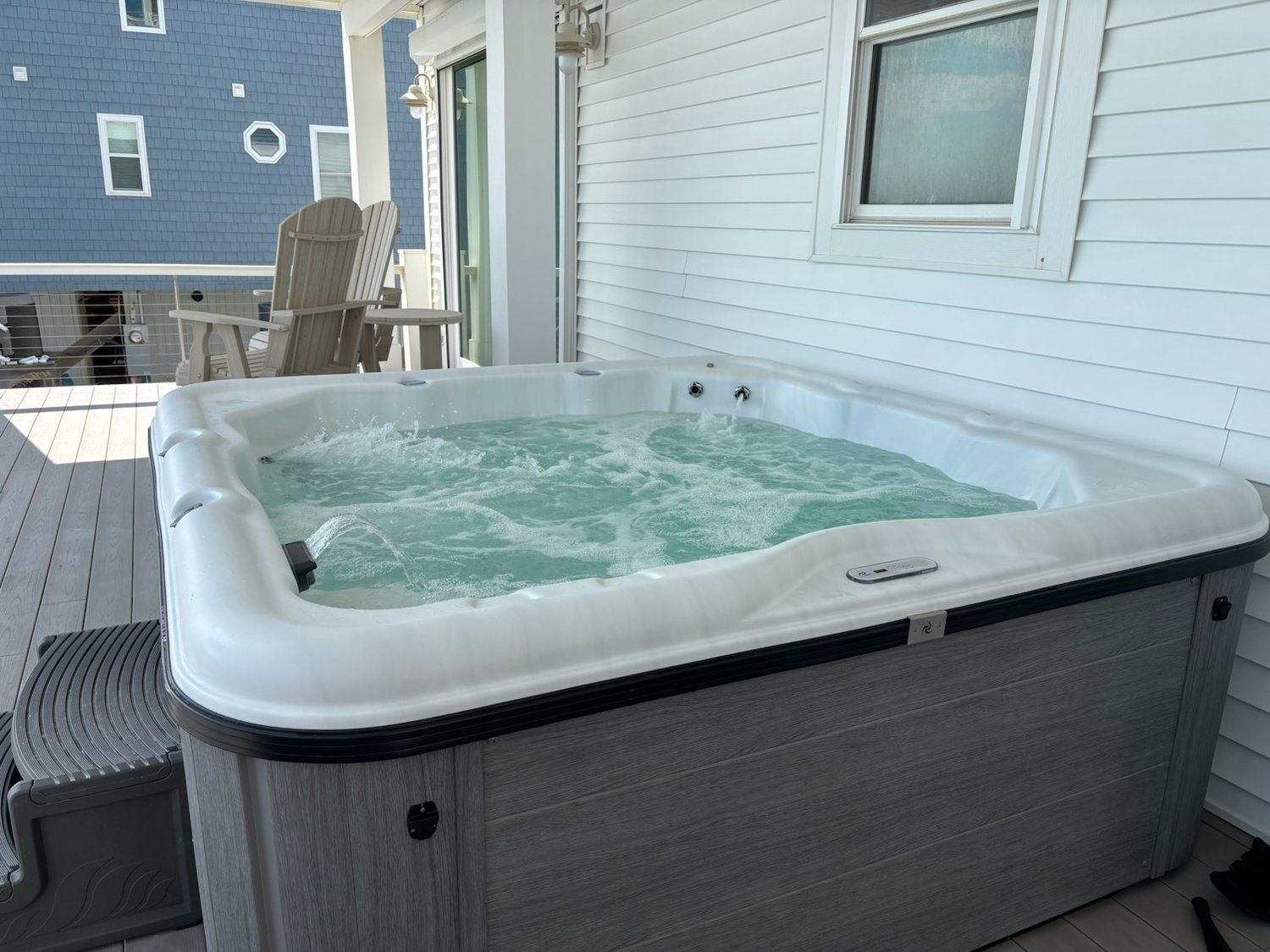 Ein Whirlpool auf einer Holzterrasse, im Hintergrund ein Haus.