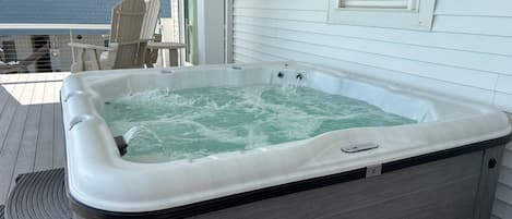Een hottub op een houten terras met een huis op de achtergrond.