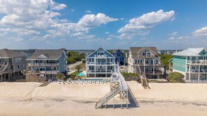A beachfront property with multiple houses, a swimming pool, and a wooden staircase leading to the beach. - On Porpoise #223 | Luxury Oceanfront Escape in North Topsail Beach (North Topsail Beach)