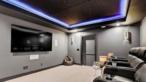 Ein Heimkinozimmer mit Flachbildfernseher, Relaxliegen, einer Popcornschüssel und einem Trinkglas.