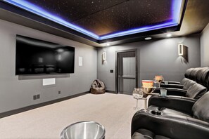Ein Heimkinozimmer mit Flachbildfernseher, Relaxliegen, einer Popcornschüssel und einem Trinkglas.