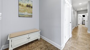 A hallway with a bench, a painting, and a door leading to another room. - Beach Walk #225-Oceanfront Duplex in Surf City, Pool, Elevator, Dog Friendly! (Surf City)