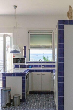 A compact kitchen with a view of the sea, a microwave, and a sink. - VILLA ANNA IN CASTELLABATE (San Marco)