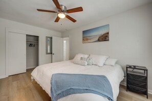 Ein Schlafzimmer mit einem Bett, einem Deckenventilator, einem Nachttisch und einem Bild an der Wand.