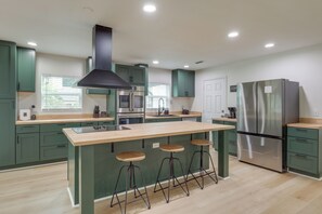A modern kitchen with green cabinets, a stainless steel refrigerator, a central island with stools, and a black range hood. - 6 Mi to Dtwn! Jacksonville Gem w/ Outdoor Oasis (Jacksonville)