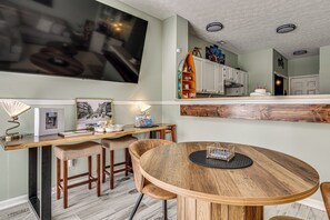 A modern kitchen with white cabinets, a wooden dining table, and a large flat-screen TV mounted on the wall. - 1 Mi to Eagle Creek Res: Family-friendly Indy Home (Indianapolis)