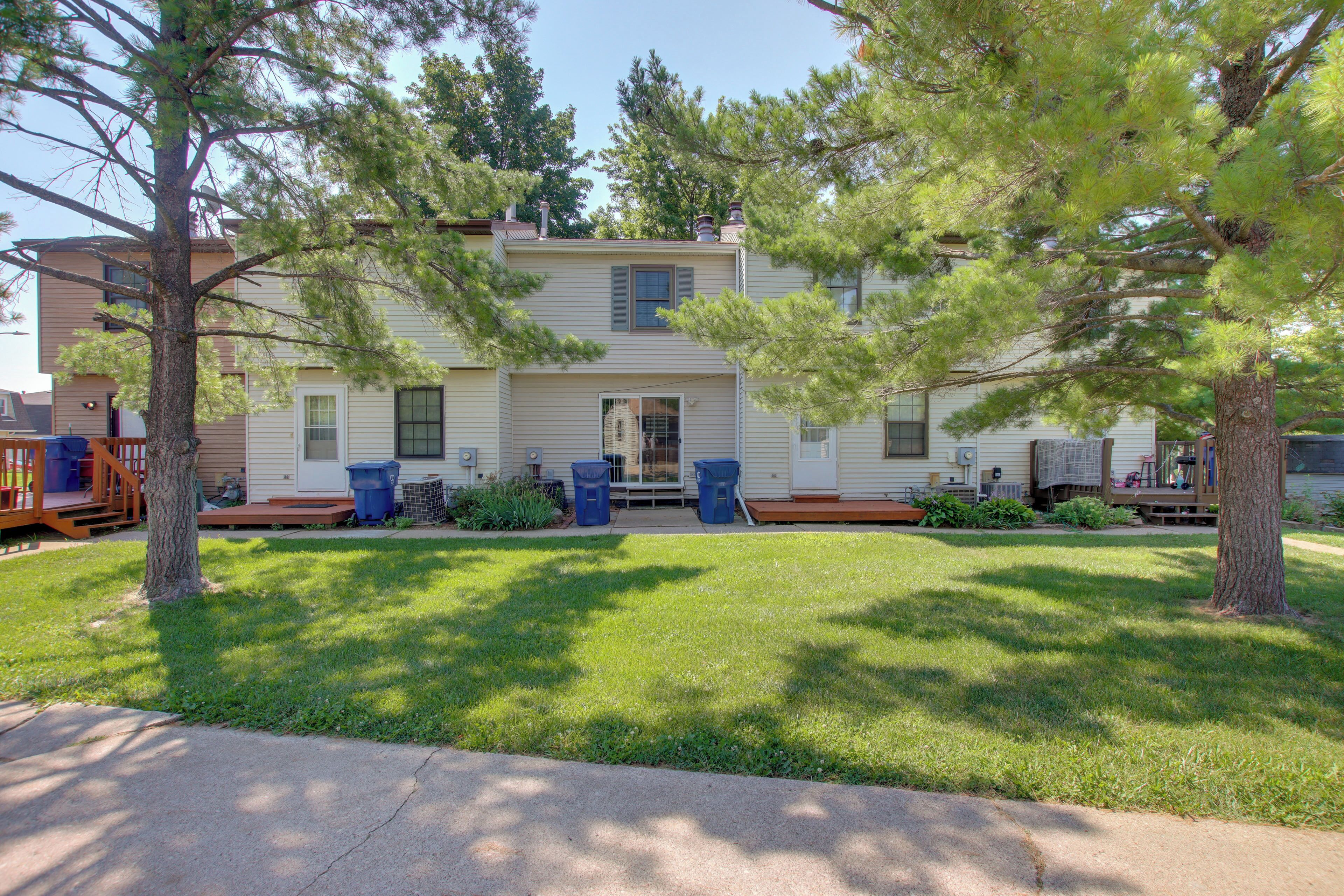 A two-story house with a front porch, a small garden, and a clear sky.