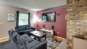 A living room with a sofa, coffee table, and a flat-screen TV mounted on the wall. - 5 Mi to Downtown Davenport! Townhome w/ Patio (Davenport)