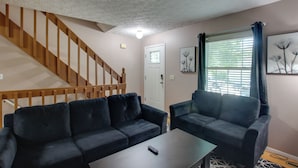 A living room with a staircase, two sofas, a coffee table, and a window with blinds. - 5 Mi to Downtown Davenport! Townhome w/ Patio (Davenport)