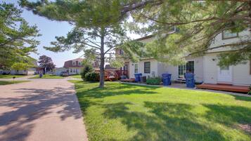 A residential street with houses, a sidewalk, and a tree.