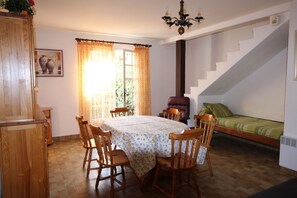 Ein Zimmer mit Esstisch, Stühlen, einem Bett, einer Treppe und einer Kandelaber.
