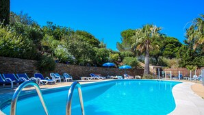 Piscina com água azul, rodeada por espreguiçadeiras e guarda-sóis.
