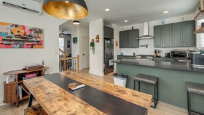 Una cocina moderna con una isla central, una zona de comedor con mesa de madera y una lámpara colgante grande.