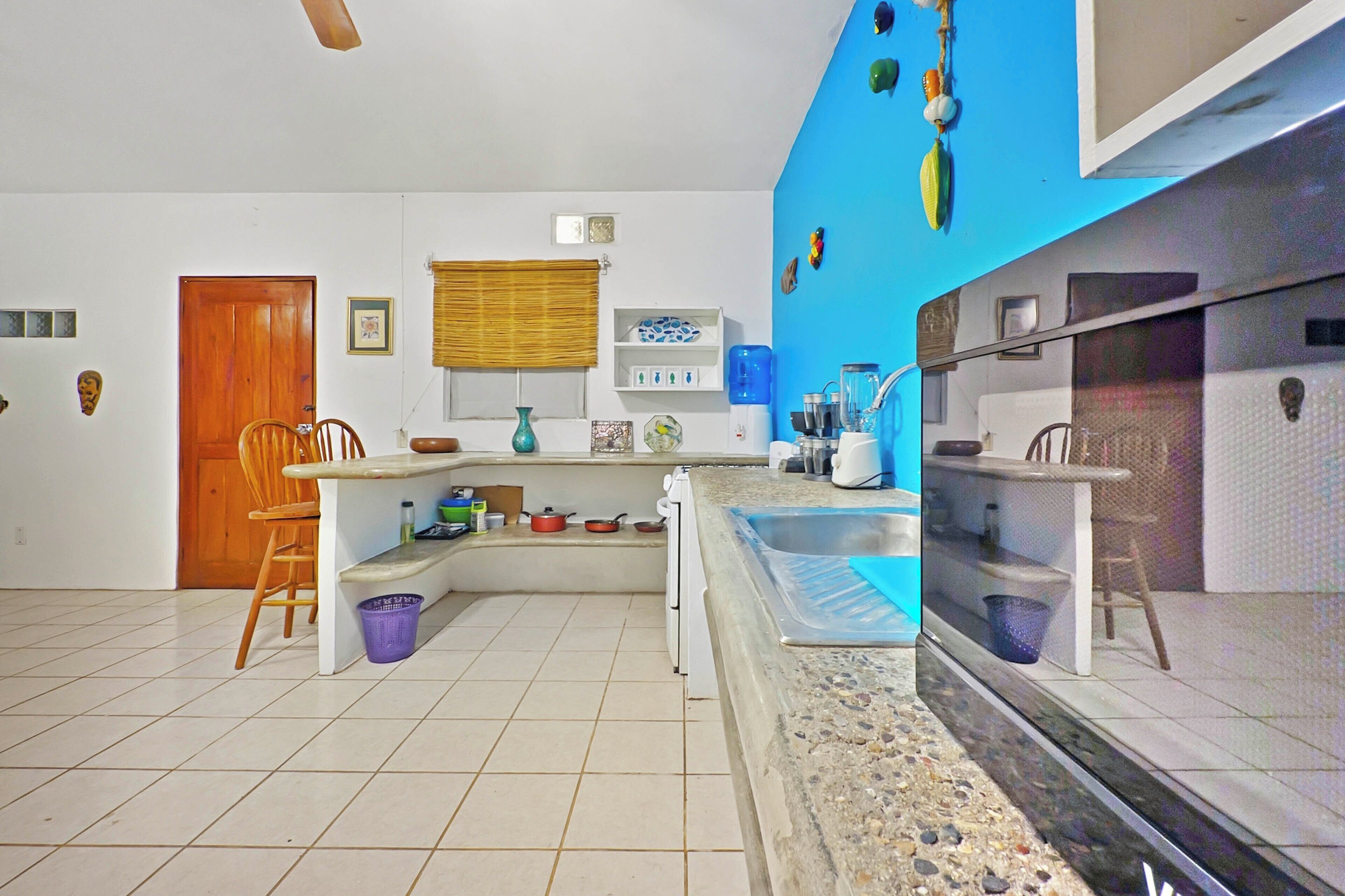 A kitchen with a built-in stove, a sink, and a window with blinds.