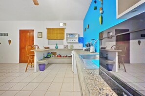 A kitchen with a built-in stove, a sink, and a window with blinds. - Quaint Condo Close to Beach and Plaza (Sayulita)