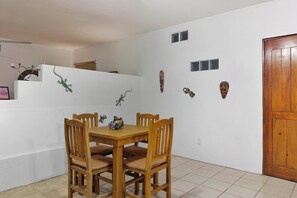 Ein Essbereich mit Holztisch und -stühlen, einer weißen Wand mit dekorativen Masken und einer Holztür.