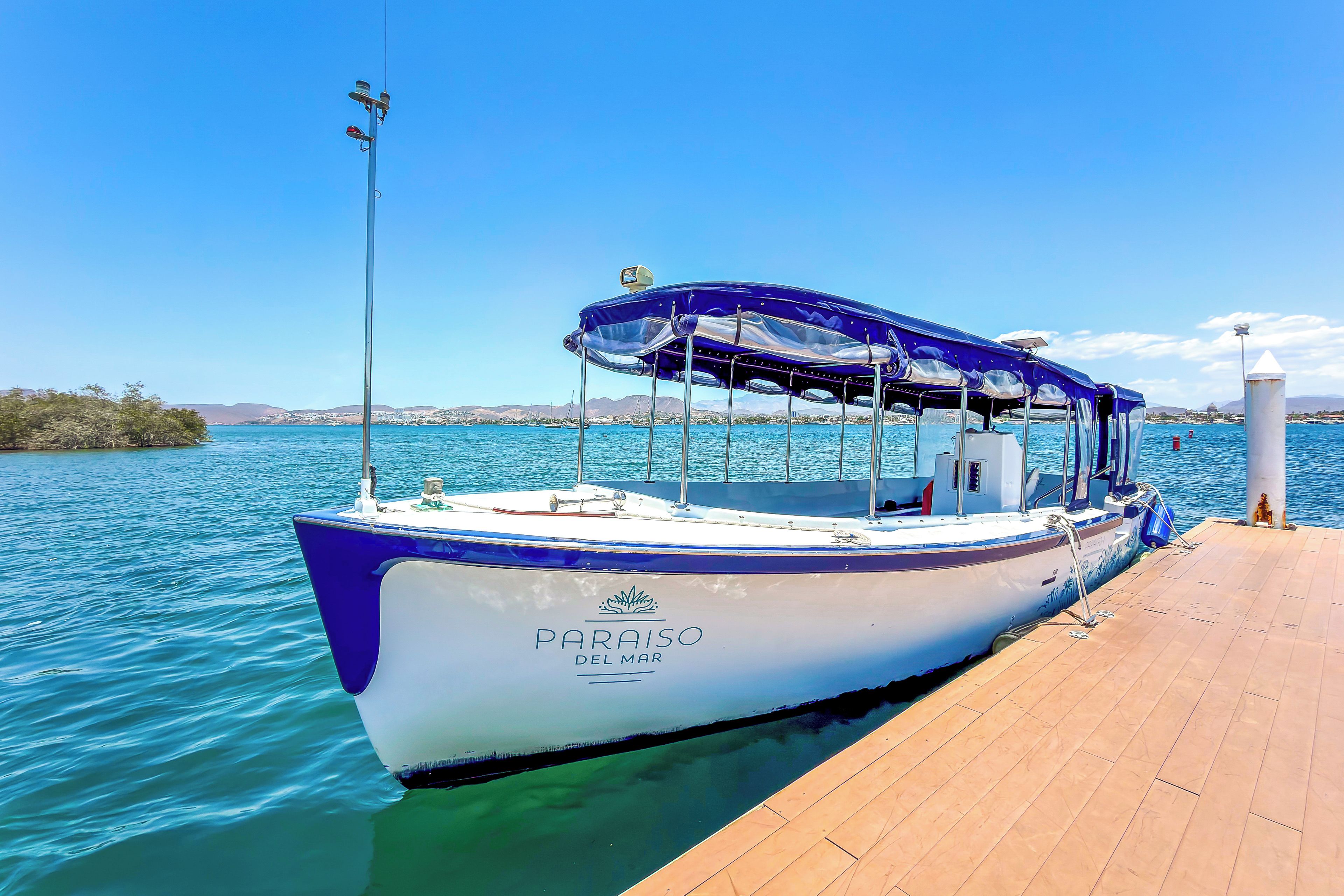 A boat docked at a pier with a clear view of the water and distant land.