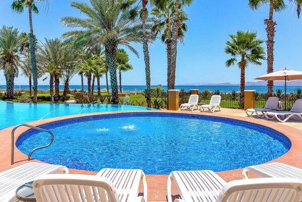 A swimming pool with lounge chairs and a view of the sea.
