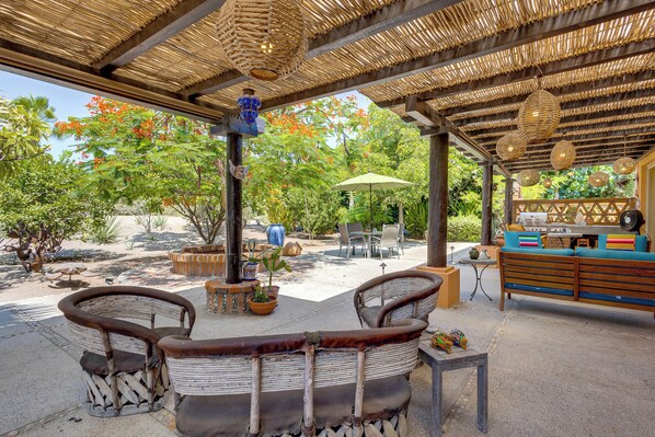 An outdoor seating area with wicker furniture, a table, and a hanging light fixture.