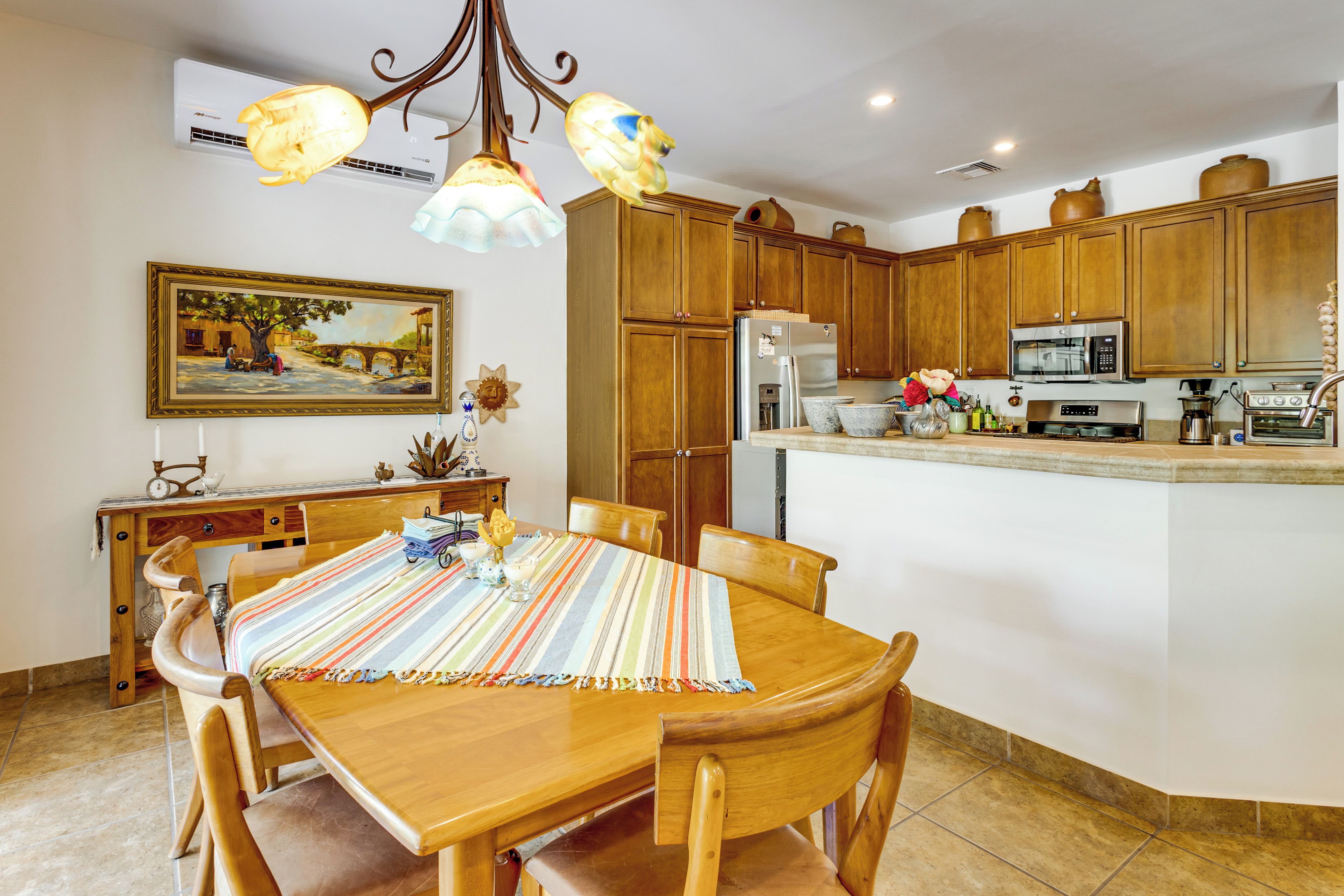 A kitchen with wooden cabinets, a refrigerator, a microwave, and a dining area with a table and chairs.