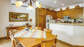 A kitchen with wooden cabinets, a refrigerator, a microwave, and a dining area with a table and chairs.