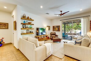 Amplia sala de estar con televisor de pantalla plana, sofás cómodos, una mesa de centro y un comedor con vistas al exterior.
