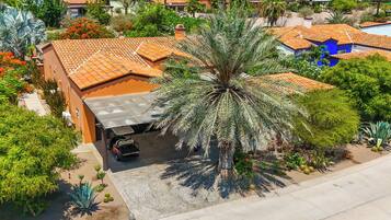 A residential area with a house featuring a tiled roof, a driveway, and a palm tree.