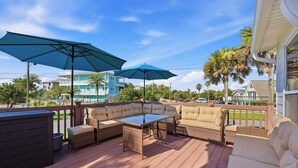 A deck with wicker furniture, two umbrellas, and a view of neighboring houses. - Walk to the Beach! St. Augustine Group Retreat (St. Augustine)