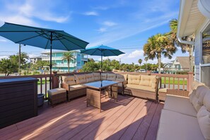 A deck with wicker furniture, two umbrellas, and a view of neighboring houses. - Walk to the Beach! St. Augustine Group Retreat (St. Augustine)