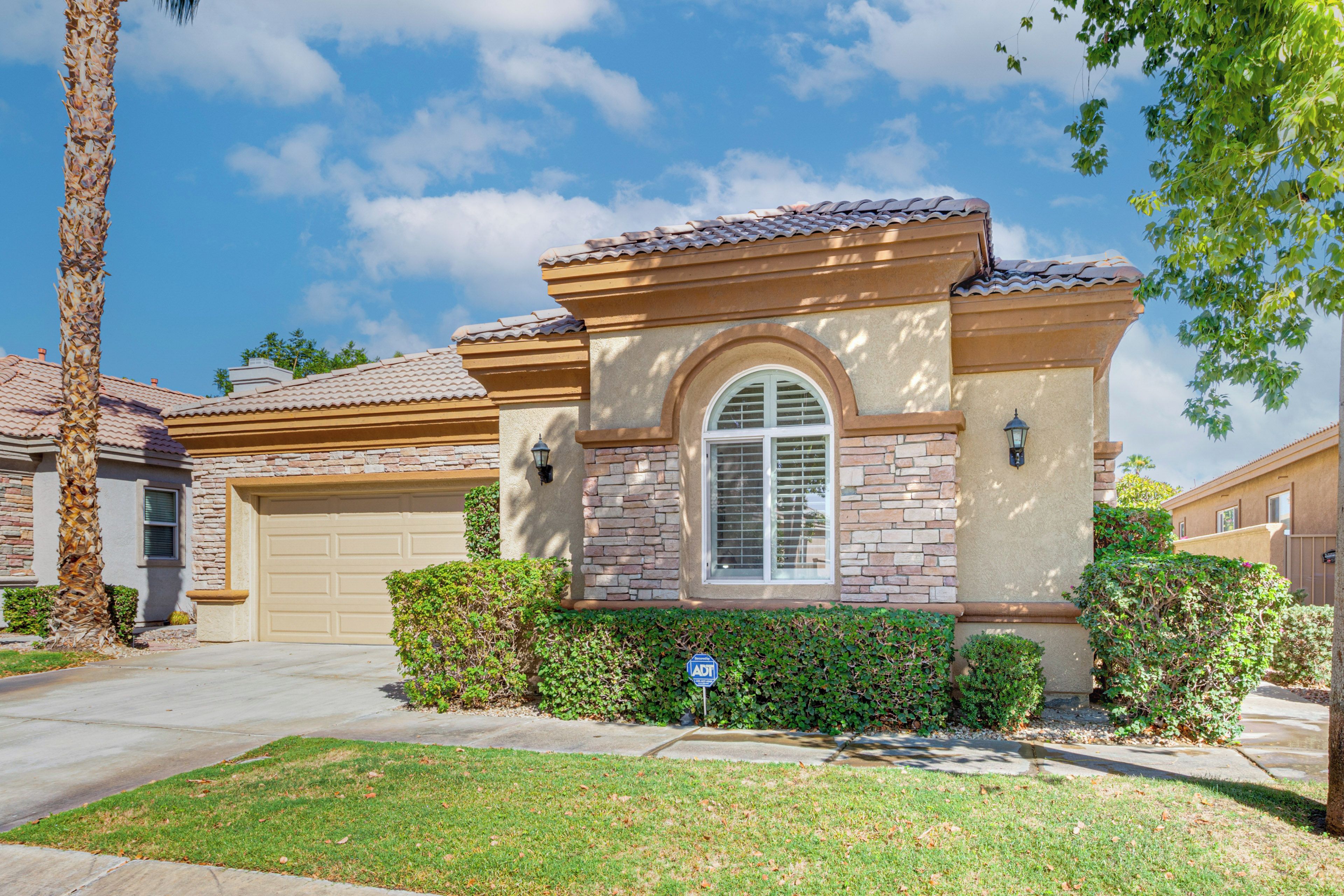 A residential house with a garage, a well-maintained lawn, and a clear sky.