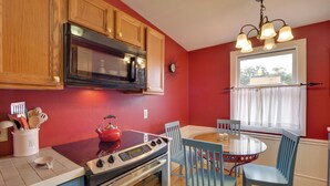 Una cocina con armarios de madera, microondas, estufa y una mesa de comedor con sillas.