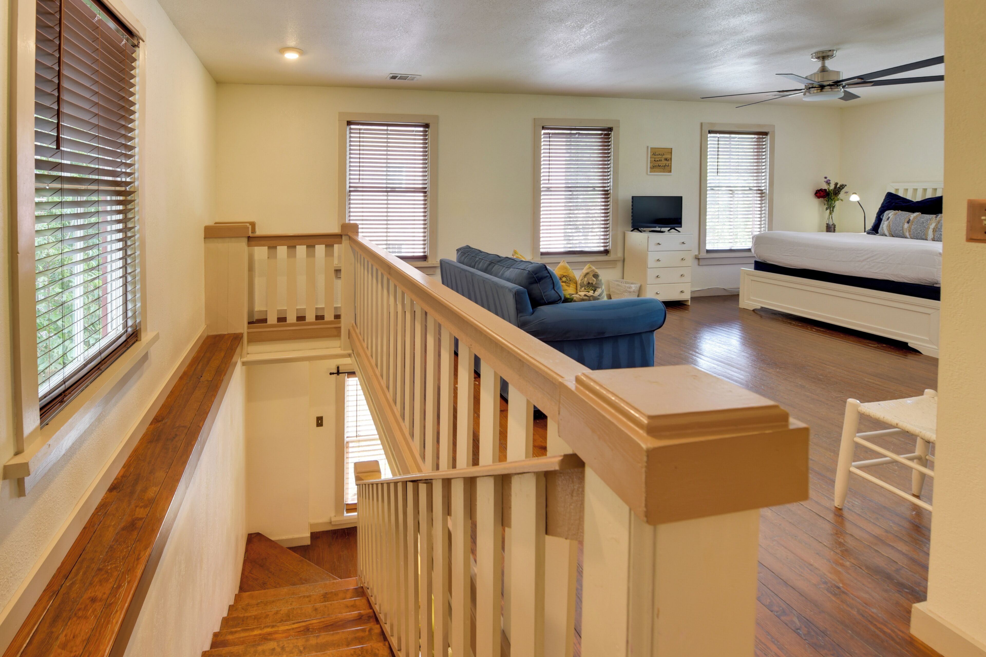A spacious room with a wooden staircase, a bed, a sofa, and a television.