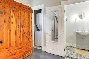 Ein Badezimmer mit Holzschrank, Waschmaschine, Spiegel und Waschbecken.