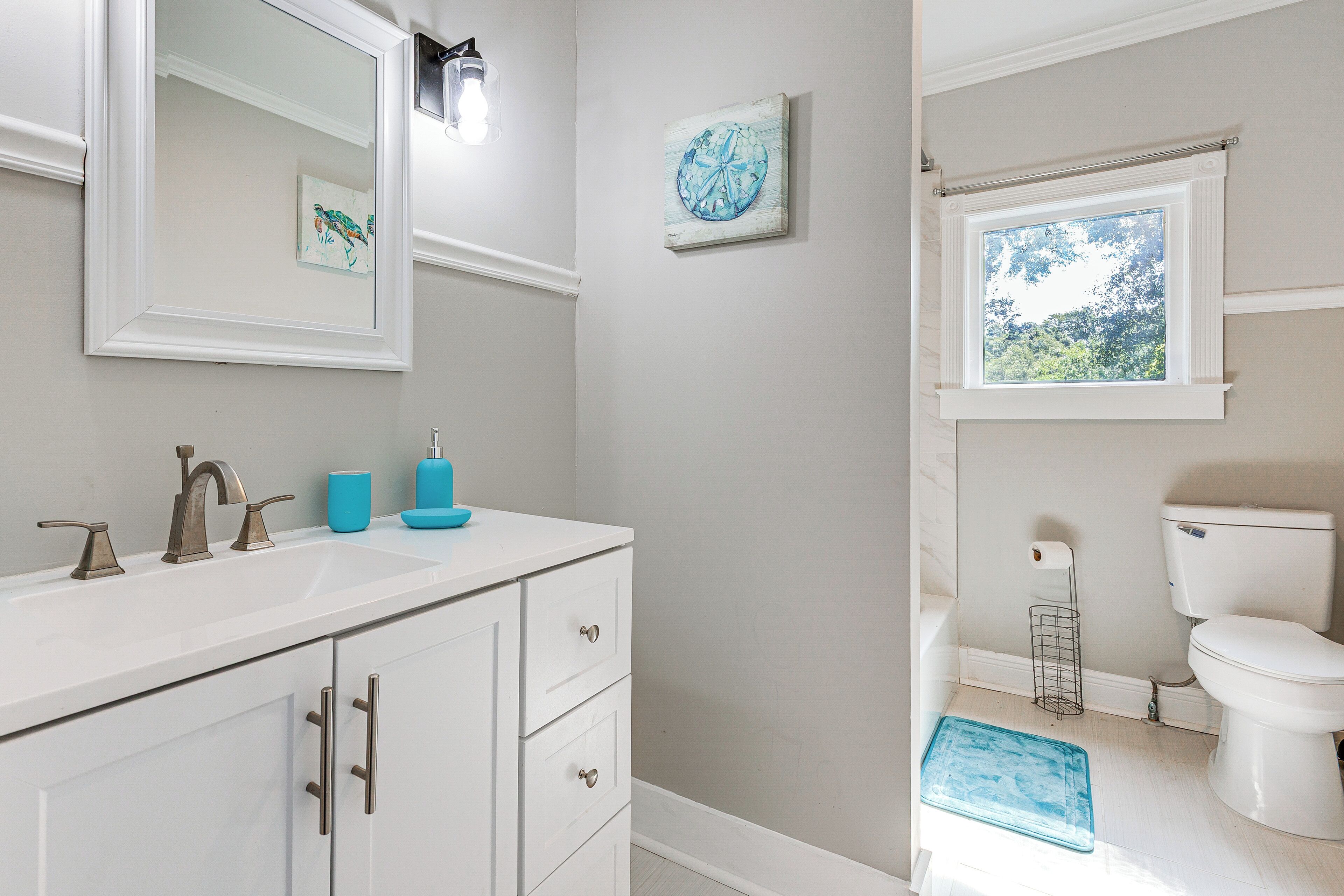 Une salle de bain avec un meuble-lavabo blanc, des toilettes et une fenêtre.