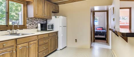 A kitchen with wooden cabinets, a white refrigerator, a microwave, and a sink.