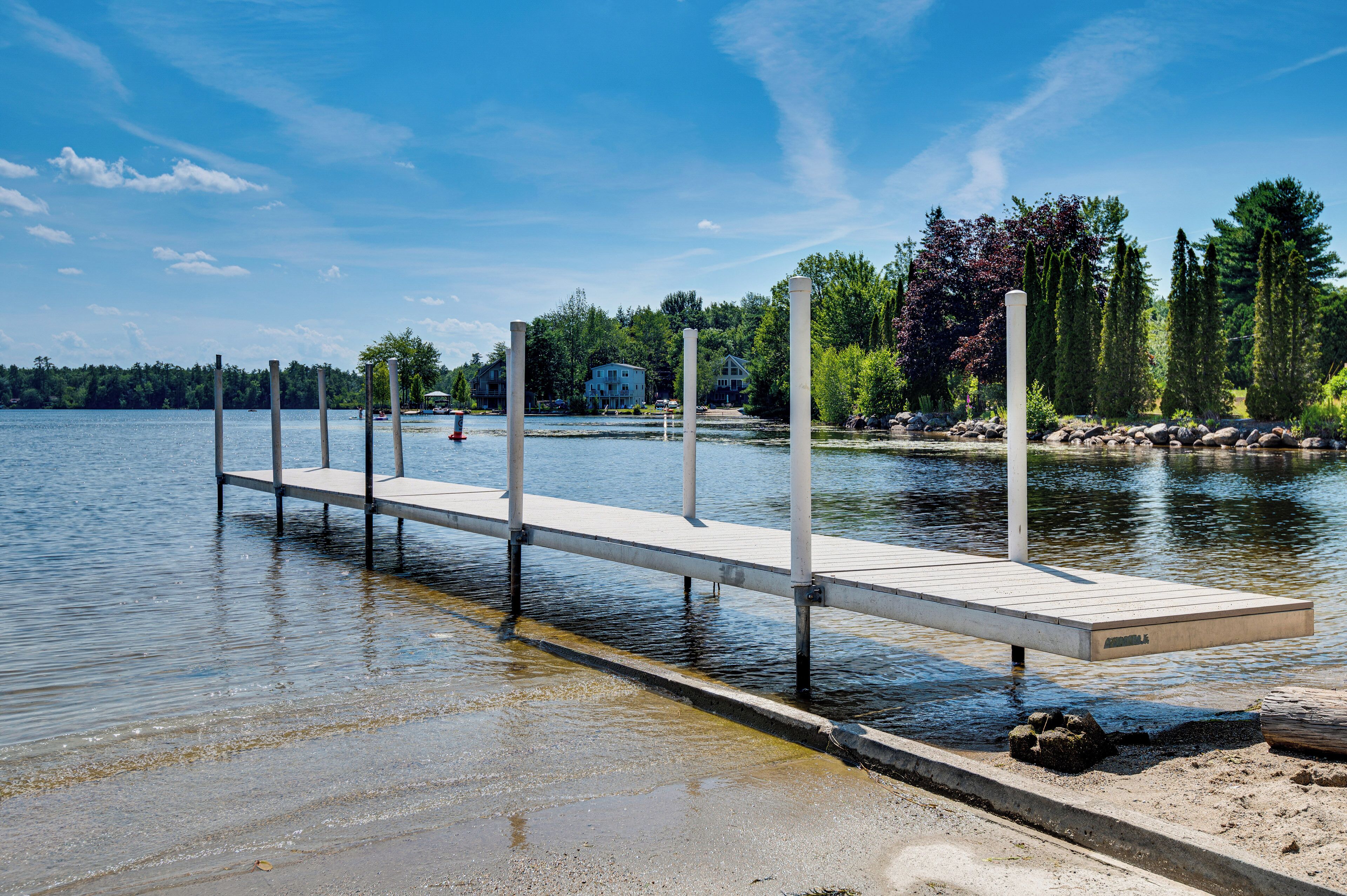 A wooden dock extending into a lake with a clear sky above.