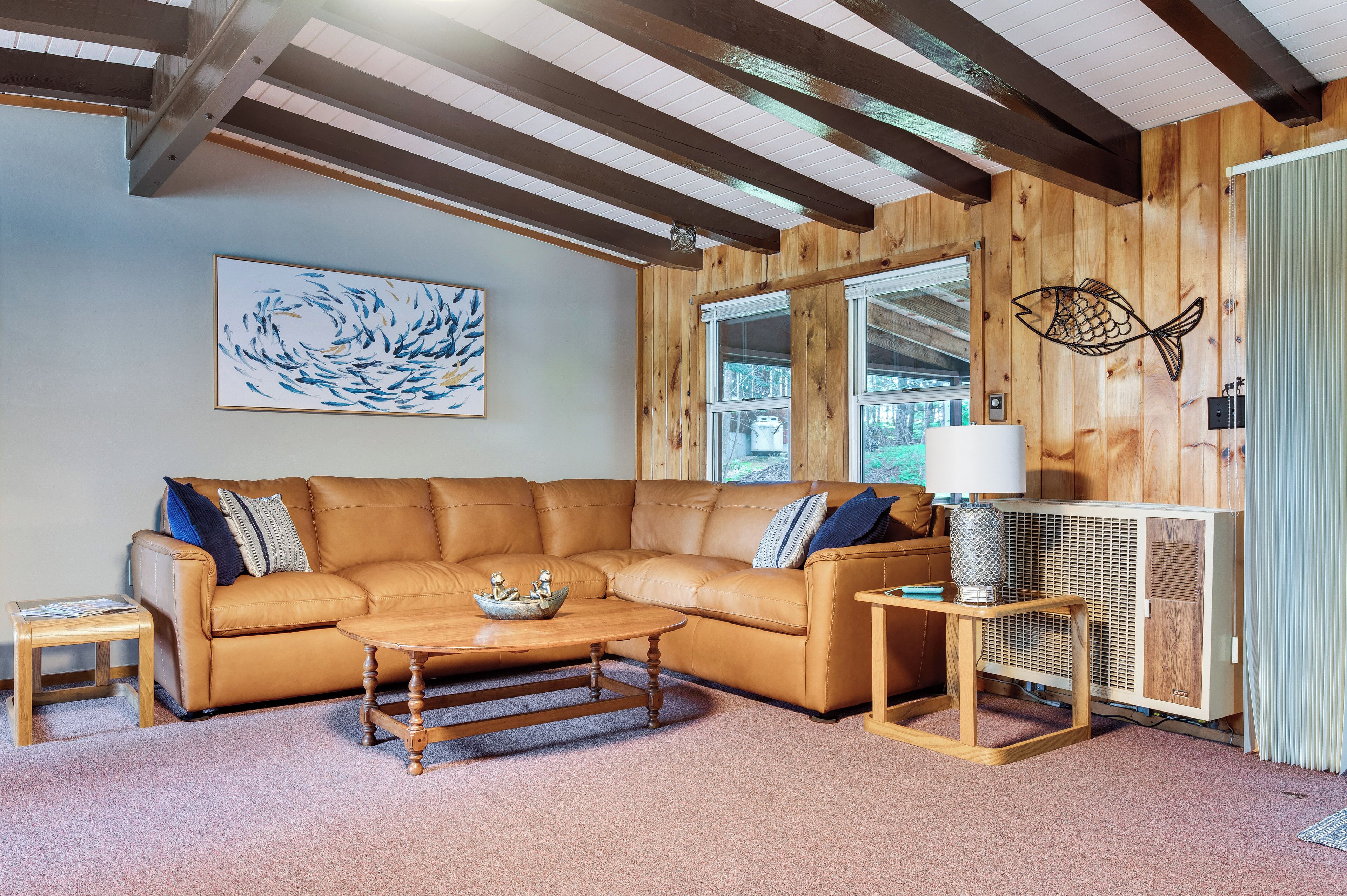A cozy living room with a brown leather sofa, a wooden coffee table, and a fish-themed wall decoration.