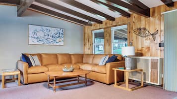 A cozy living room with a brown leather sofa, a wooden coffee table, and a fish-themed wall decoration.