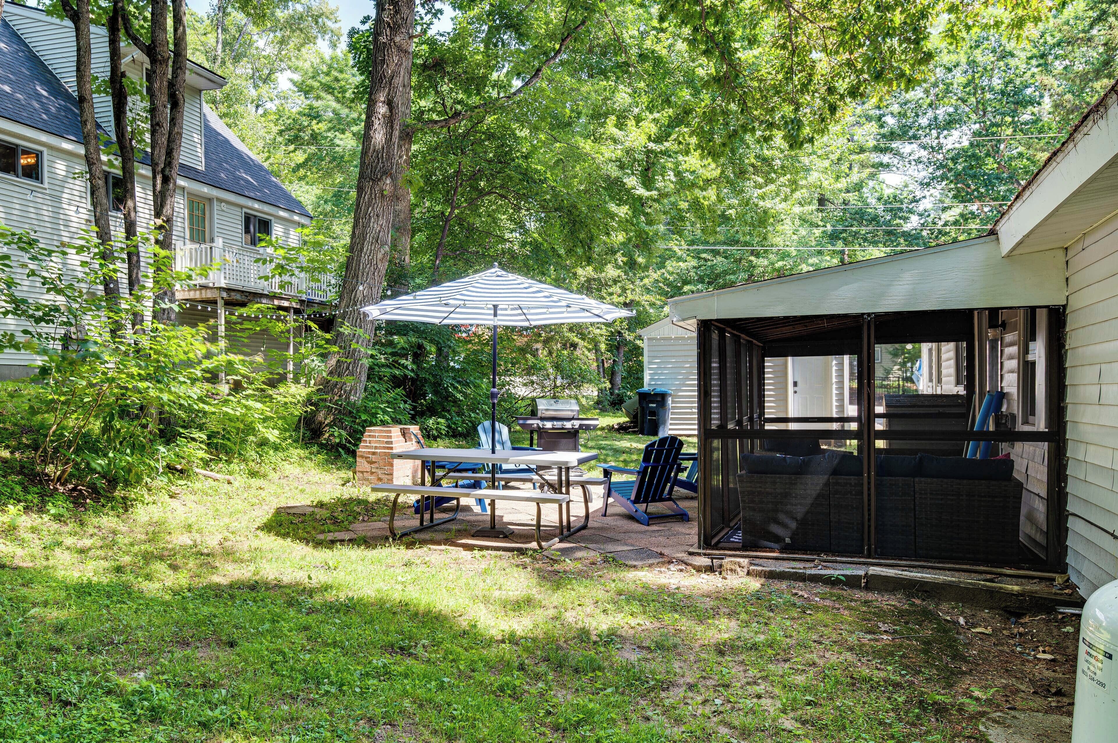 A backyard with a covered patio, a grill, and outdoor seating.
