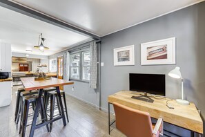 Une cuisine moderne avec une table en bois, des tabourets de bar et une grande fenêtre.