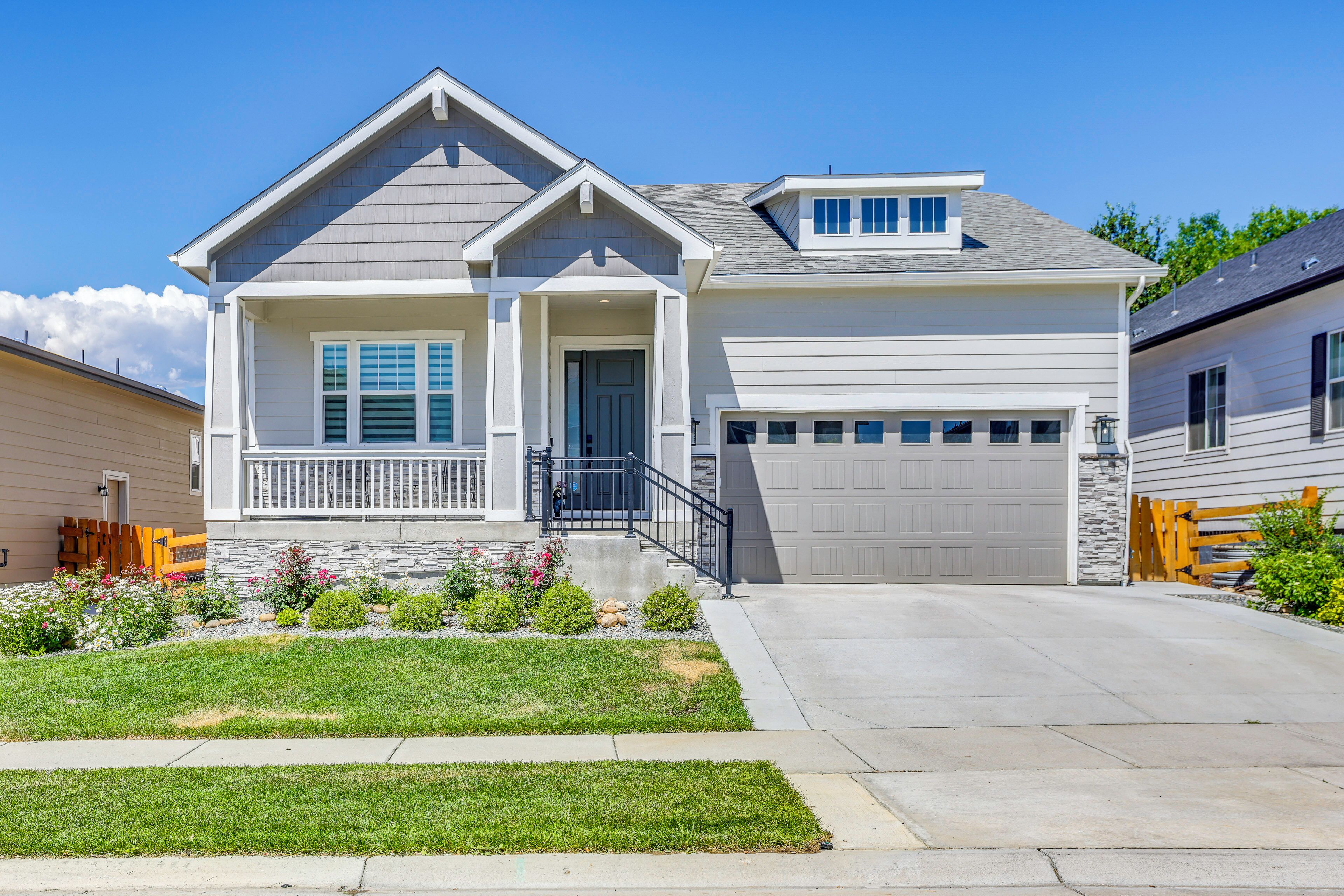 A two-story house with a front porch, a garage, and a well-maintained lawn.