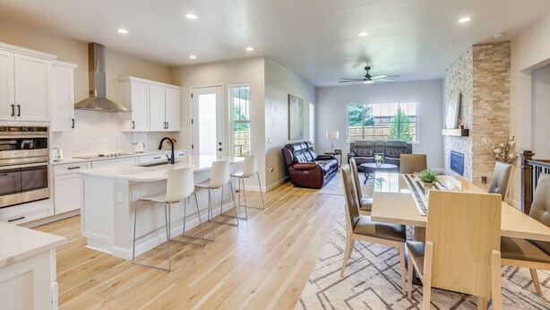 A modern kitchen with white cabinets, a central island, and a dining area with a wooden table and chairs. - Great for Families! Arvada Haven w/ Yard & Patio (Arvada)