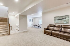 A spacious living area with a brown leather sofa, a wooden staircase, and a billiards table. - Great for Families! Arvada Haven w/ Yard & Patio (Arvada)