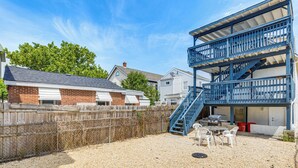 A multi-story building with a blue staircase, a fenced backyard, and outdoor seating.