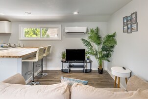 Una cocina moderna con barra, televisor de pantalla plana y mesa de comedor.