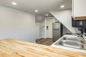 Cocina con encimera de madera, pileta de acero inoxidable y refrigerador.