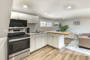 Una cocina moderna con armarios blancos, horno empotrado, encimera de madera y una pequeña isla con lavamanos.
