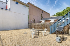 An outdoor patio area with a table and chairs, a barbecue grill, and a blue staircase.