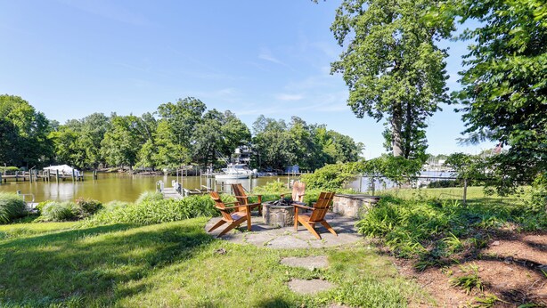 Un patio junto al lago con mobiliario exterior y vistas a barcos.