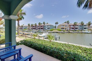 A marina with boats docked, a water body, and a row of multi-story buildings with balconies.